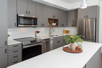 a modern kitchen with stainless steel appliances and white countertops